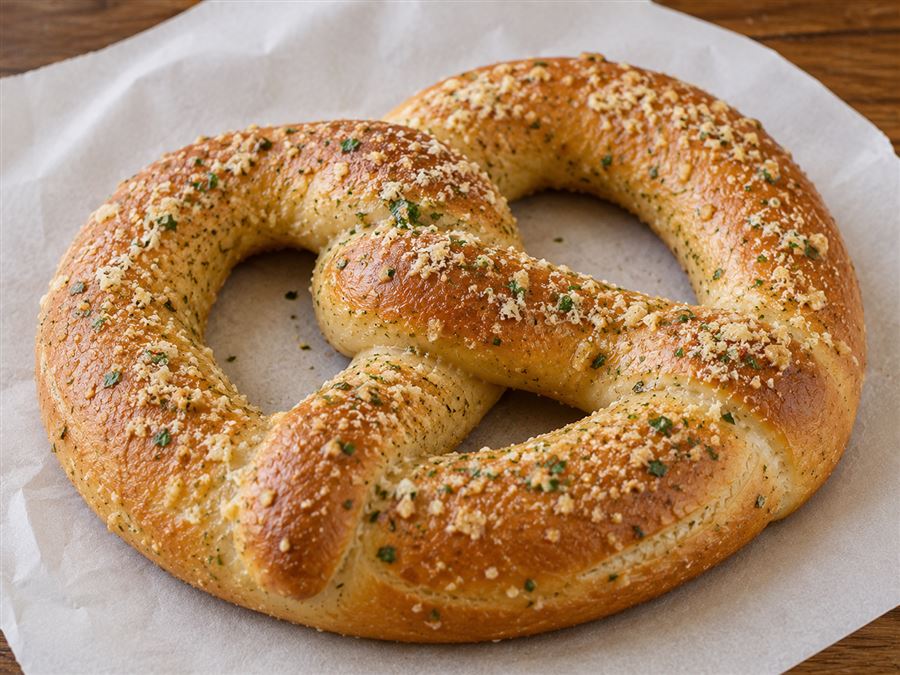 Soft pretzel topped with garlic butter, parmesan, and herbs